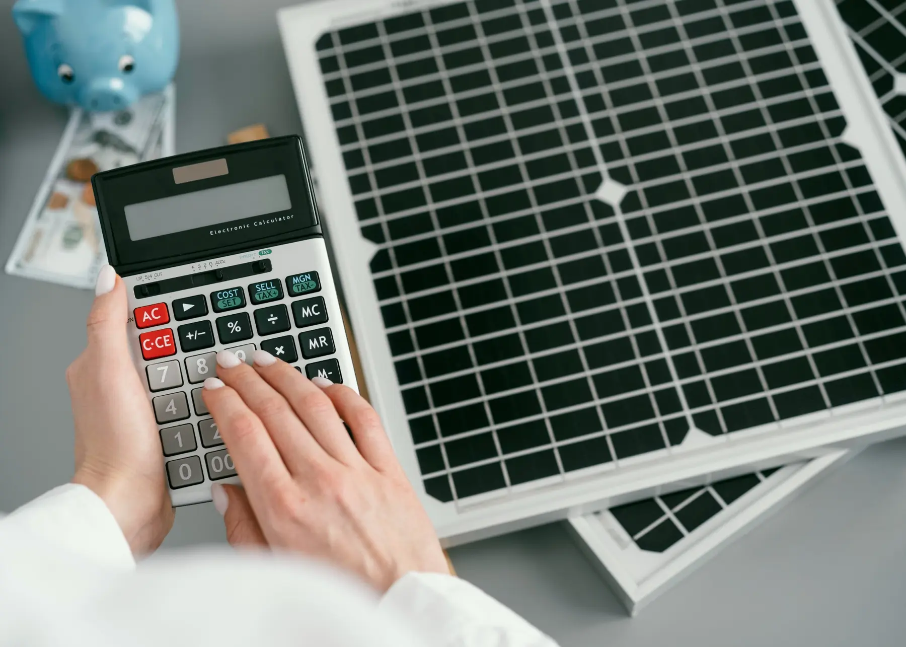 Solar finance feasibility calculation using a calculator beside photovoltaic panels
